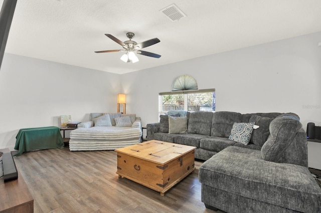 living room with a ceiling fan, visible vents, and dark wood-style flooring