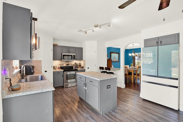 kitchen featuring gray cabinets, a kitchen island, stainless steel appliances, and a sink