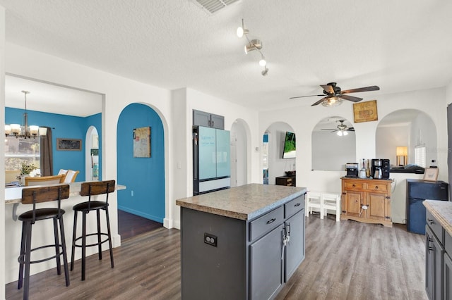 kitchen featuring gray cabinets, visible vents, dark wood finished floors, and freestanding refrigerator