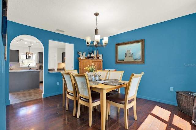 dining room with a chandelier, dark wood finished floors, visible vents, and baseboards