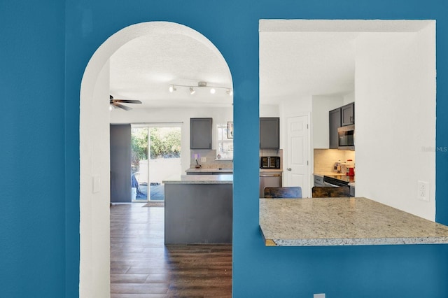 kitchen featuring decorative backsplash, ceiling fan, dark wood-type flooring, a textured ceiling, and black appliances