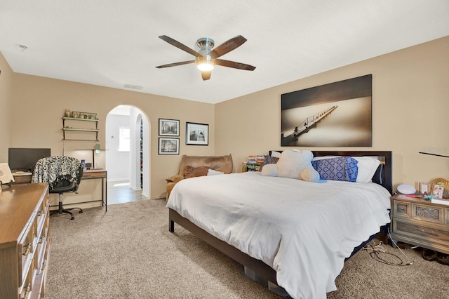 carpeted bedroom with arched walkways, visible vents, and a ceiling fan