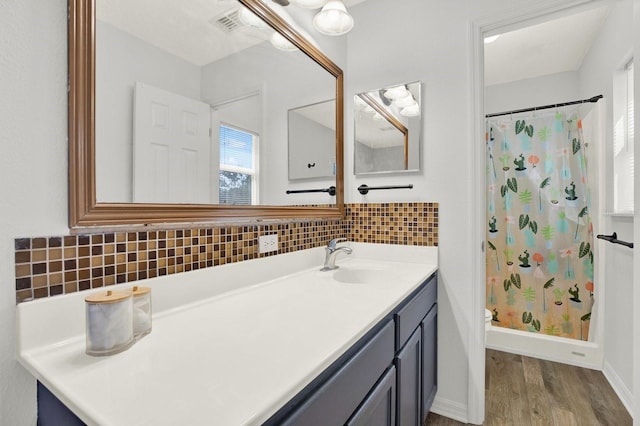 full bath featuring baseboards, a shower with curtain, wood finished floors, vanity, and backsplash