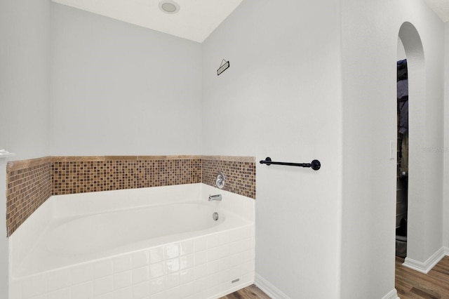 bathroom featuring a garden tub, baseboards, and wood finished floors