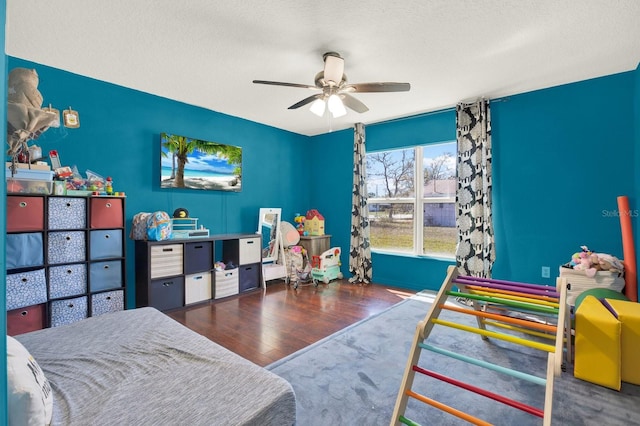 bedroom with a textured ceiling, wood finished floors, and a ceiling fan