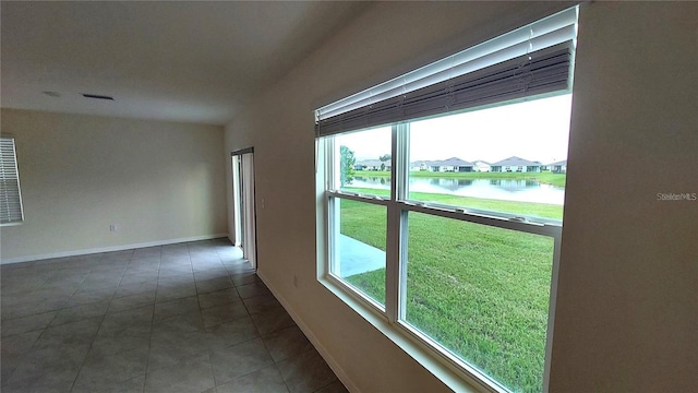 tiled spare room with a water view, visible vents, and baseboards