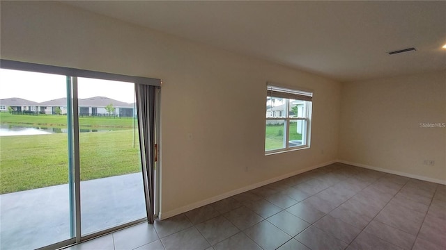 interior space featuring a water view, tile patterned flooring, visible vents, and baseboards