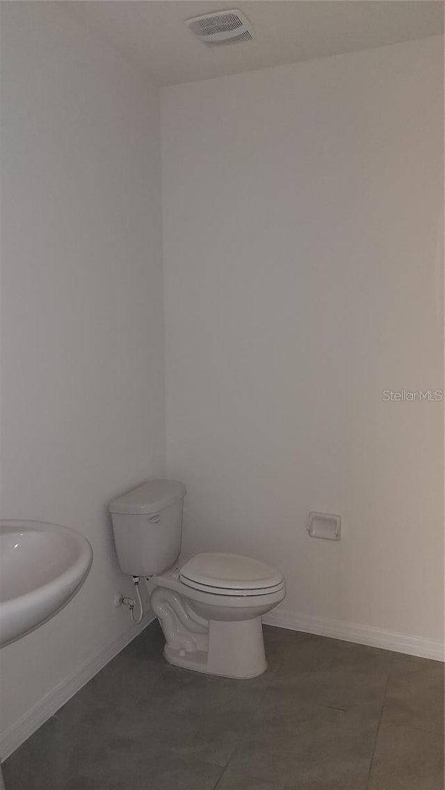 half bathroom featuring toilet, tile patterned floors, visible vents, and baseboards