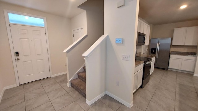 kitchen featuring light tile patterned floors, stainless steel appliances, and white cabinetry