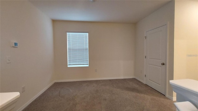 carpeted spare room featuring baseboards