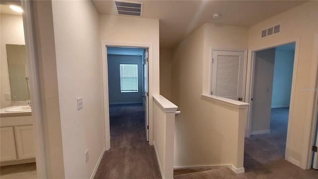 corridor with a sink, carpet, an upstairs landing, and visible vents