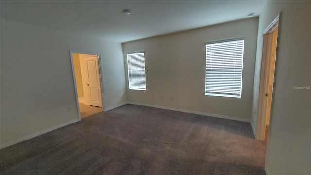 empty room featuring carpet and baseboards