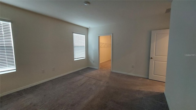 unfurnished bedroom featuring carpet, a spacious closet, baseboards, and a closet