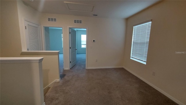 corridor with baseboards, carpet, visible vents, and attic access