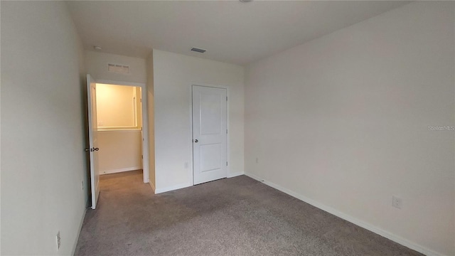 unfurnished bedroom featuring visible vents, dark carpet, and baseboards