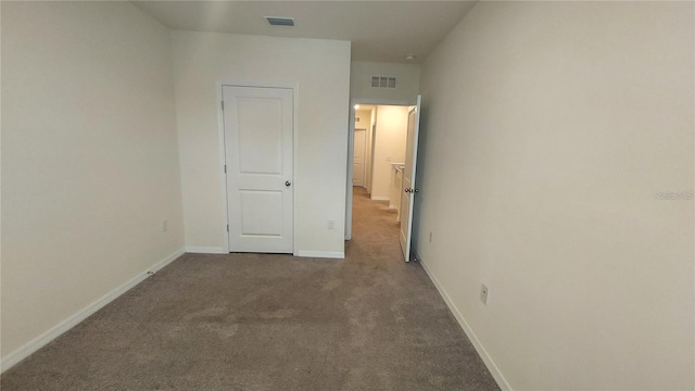 unfurnished bedroom with baseboards, visible vents, and dark colored carpet