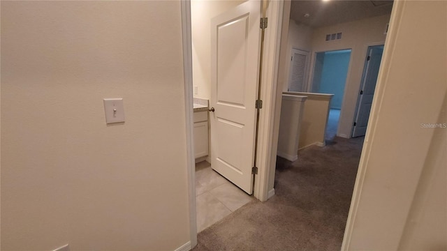 corridor featuring light carpet, baseboards, and visible vents