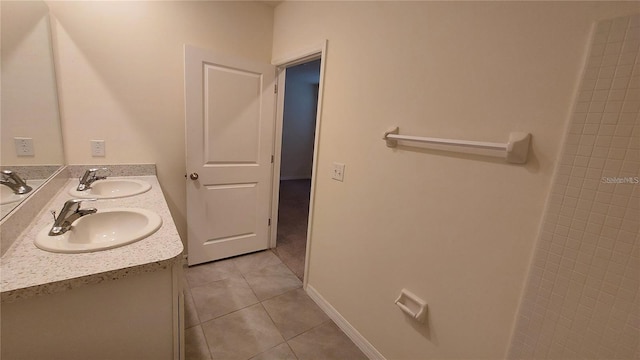 full bath featuring double vanity, baseboards, a sink, and tile patterned floors