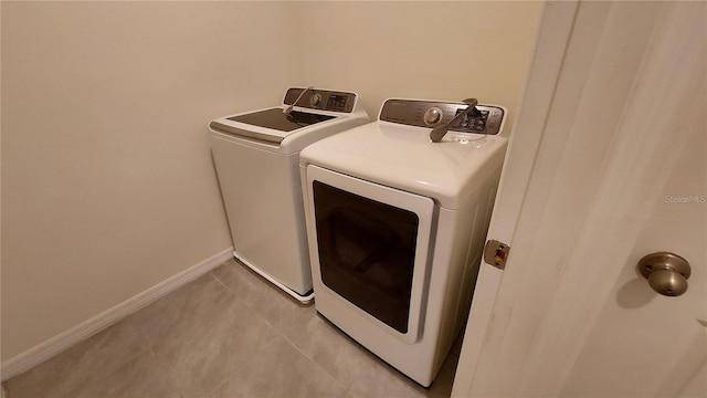 clothes washing area with laundry area, baseboards, washer and dryer, and light tile patterned flooring