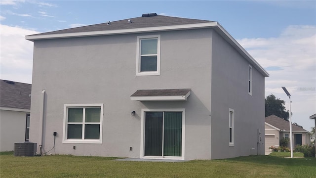 rear view of house featuring stucco siding, a yard, and central air condition unit