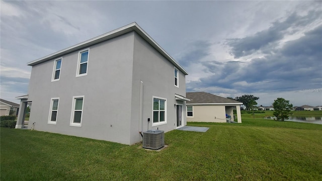 rear view of property with central AC, a yard, and stucco siding