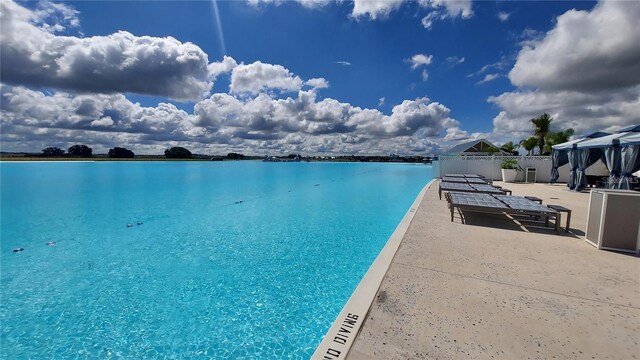 view of pool featuring a patio, a water view, and fence