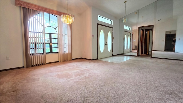 carpeted entrance foyer with baseboards, a towering ceiling, and a notable chandelier