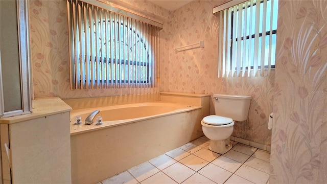 bathroom featuring toilet, wallpapered walls, a healthy amount of sunlight, and a garden tub