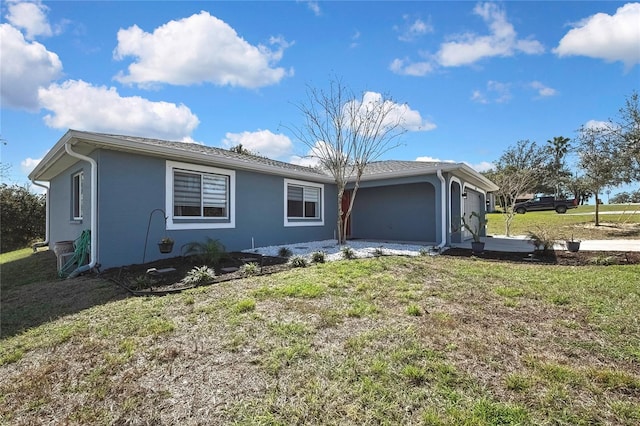 single story home featuring a garage, a front lawn, and stucco siding