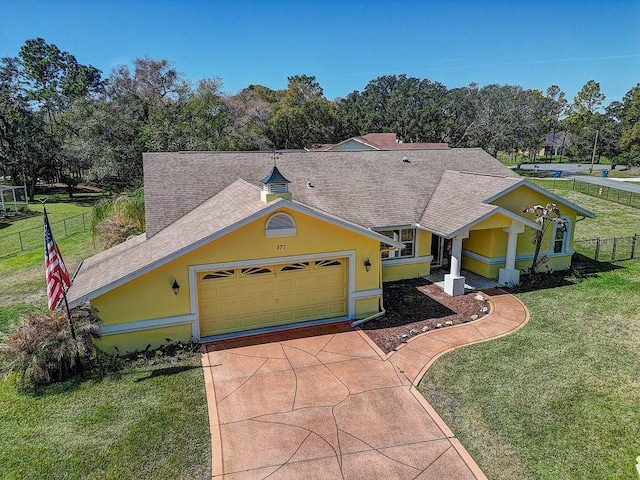 view of front of house featuring driveway, a front lawn, fence, and stucco siding