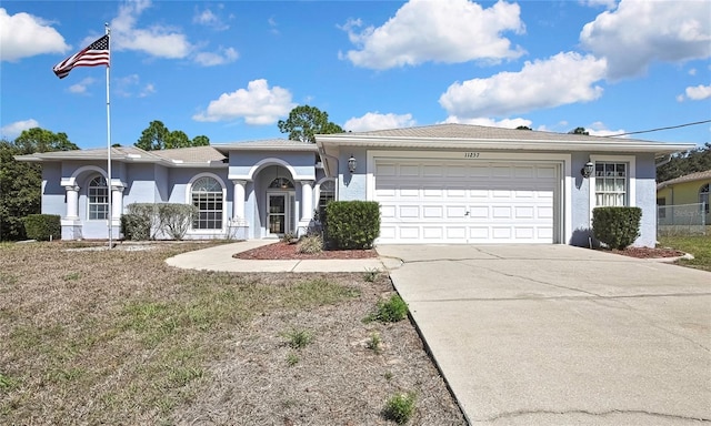 ranch-style house featuring a garage, driveway, and stucco siding