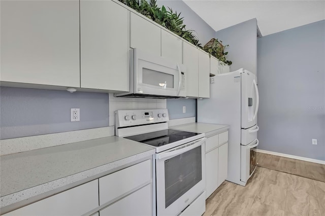 kitchen with white cabinets, white appliances, light wood-type flooring, and light countertops