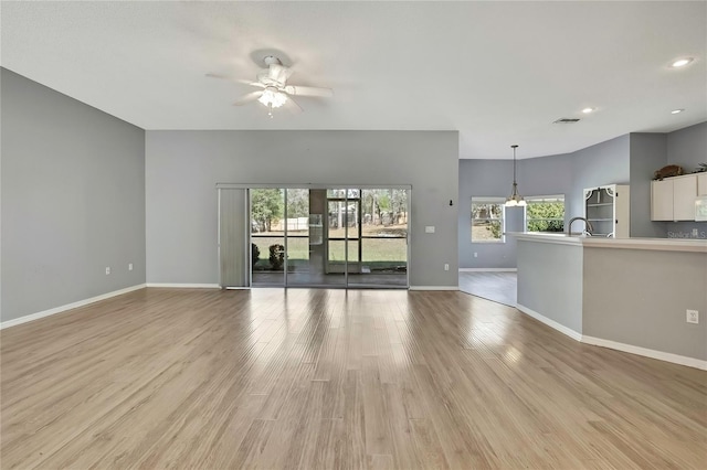 unfurnished living room featuring visible vents, ceiling fan, light wood-style flooring, and baseboards