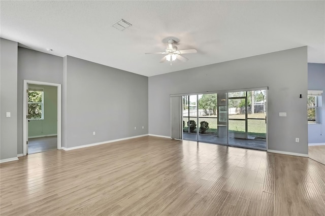 empty room with ceiling fan, wood finished floors, visible vents, and baseboards