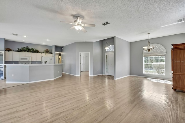 unfurnished living room with ceiling fan with notable chandelier, a textured ceiling, visible vents, and light wood-style floors