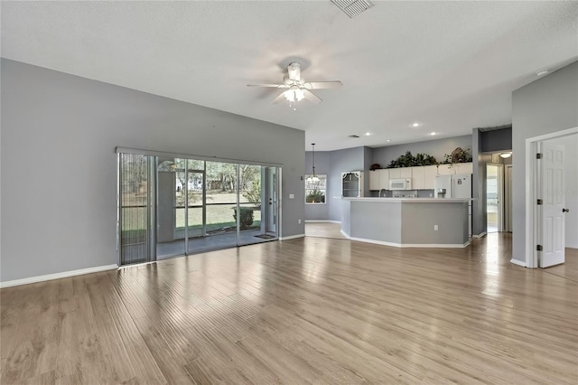 unfurnished living room with visible vents, light wood-style flooring, a ceiling fan, a textured ceiling, and baseboards