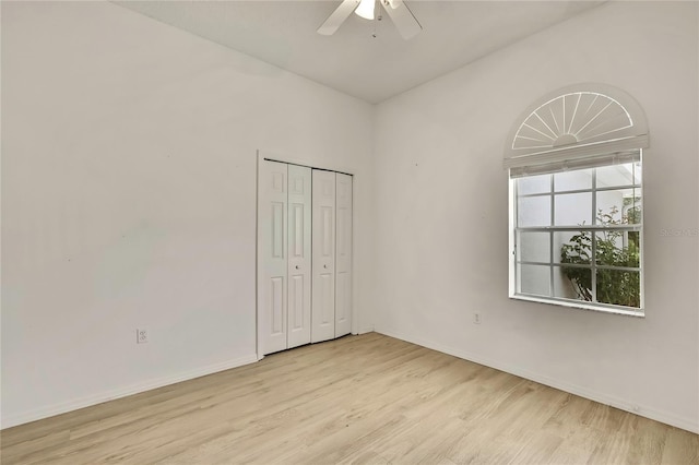 unfurnished bedroom featuring a ceiling fan, a closet, light wood-style flooring, and baseboards