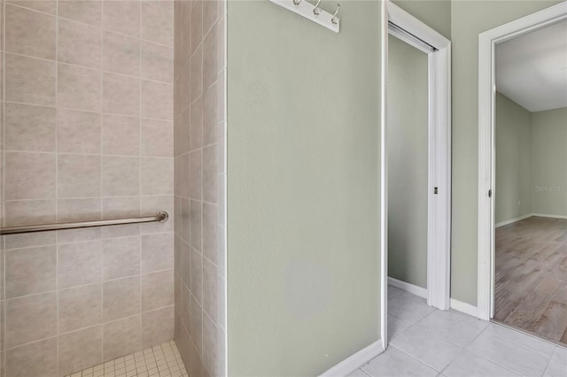 full bathroom with tiled shower, tile patterned flooring, and baseboards