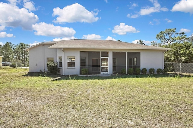 rear view of house featuring a sunroom, stucco siding, a yard, and fence