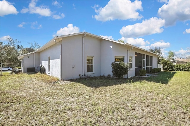 view of property exterior with central air condition unit, a lawn, fence, and stucco siding