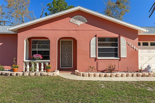 view of front facade featuring a front yard, a garage, and stucco siding