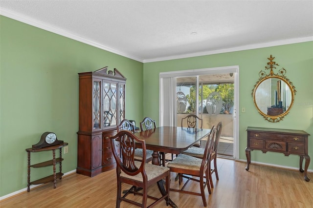 dining room with crown molding, light wood-style flooring, baseboards, and a textured ceiling