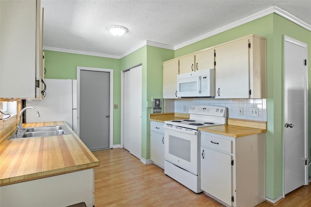 kitchen with white appliances, light wood-type flooring, a sink, crown molding, and tasteful backsplash