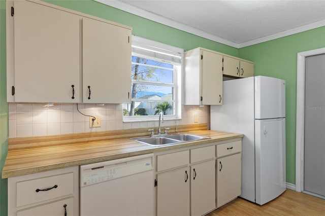 kitchen featuring white appliances, a sink, light countertops, crown molding, and tasteful backsplash