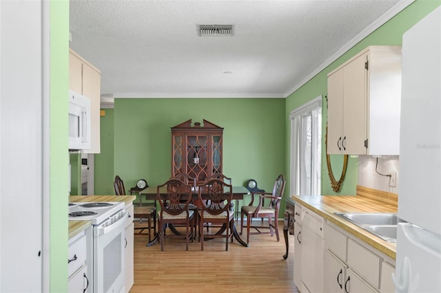 kitchen featuring visible vents, light countertops, light wood-type flooring, white appliances, and a sink