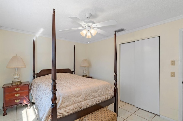 bedroom with light tile patterned floors, visible vents, a closet, a textured ceiling, and crown molding