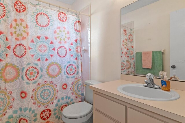 bathroom featuring curtained shower, toilet, and vanity