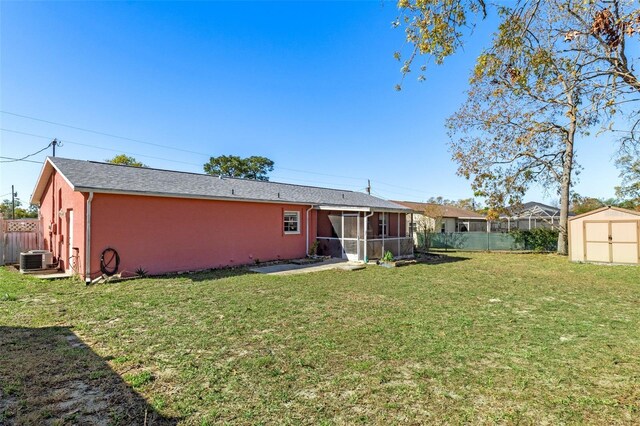 back of property with a yard, an outdoor structure, a storage shed, and a fenced backyard