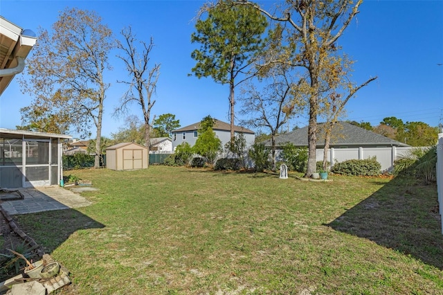 view of yard featuring an outbuilding, a storage unit, a fenced backyard, and a sunroom