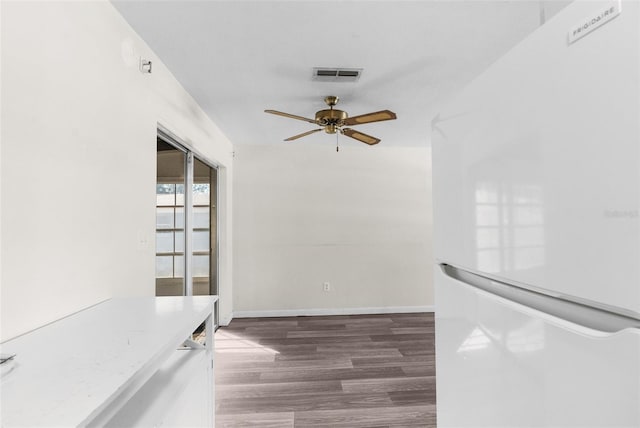 interior space featuring wood finished floors, visible vents, baseboards, a ceiling fan, and freestanding refrigerator